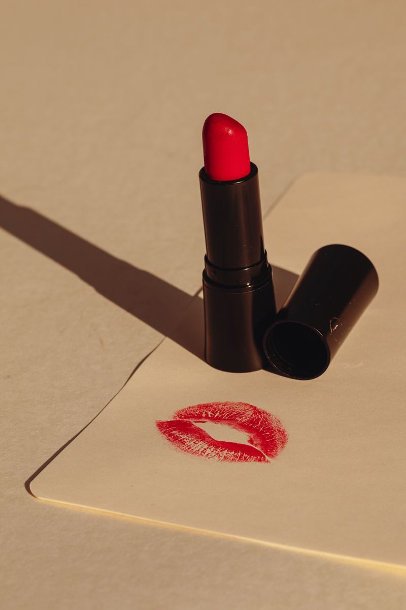 A sophisticated still life of red lipstick beside a matching lip print on paper.