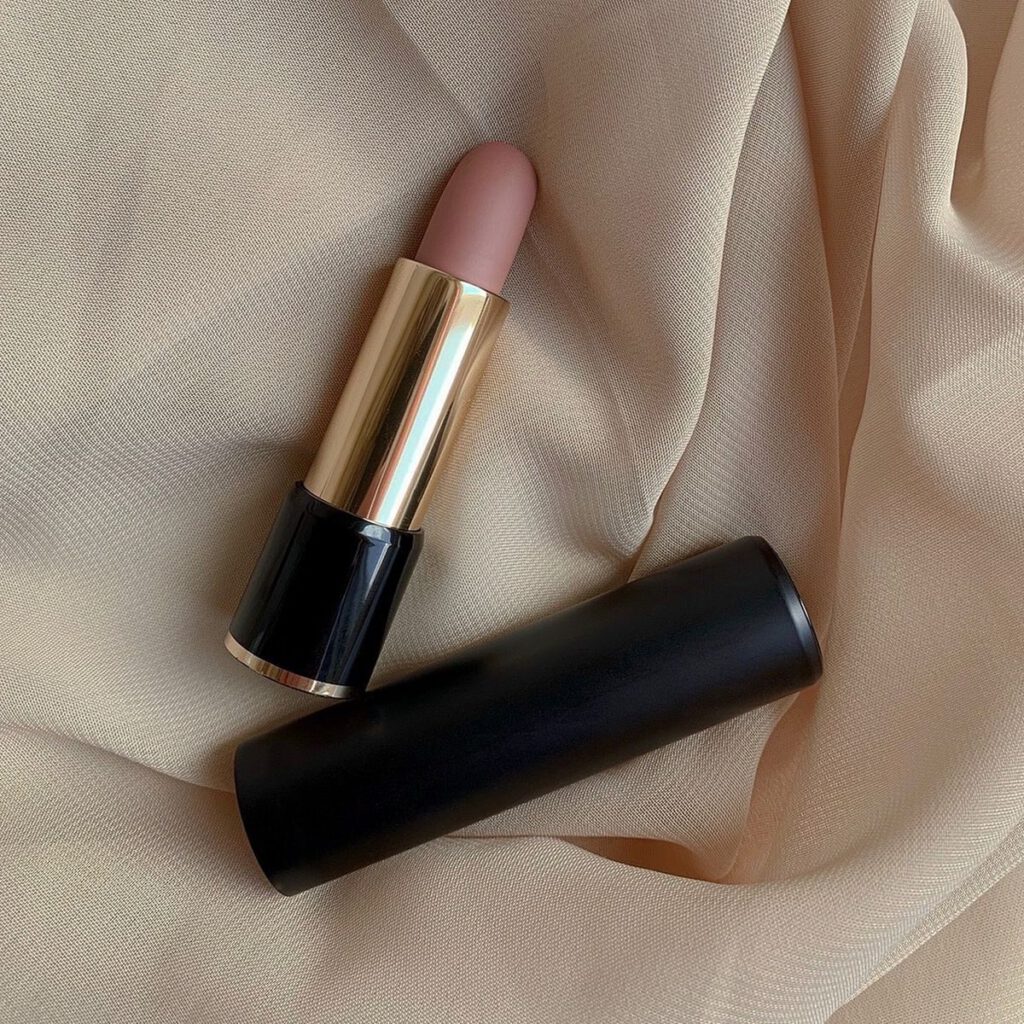 Stylish nude color lipstick on soft beige fabric, perfect for cosmetics marketing.